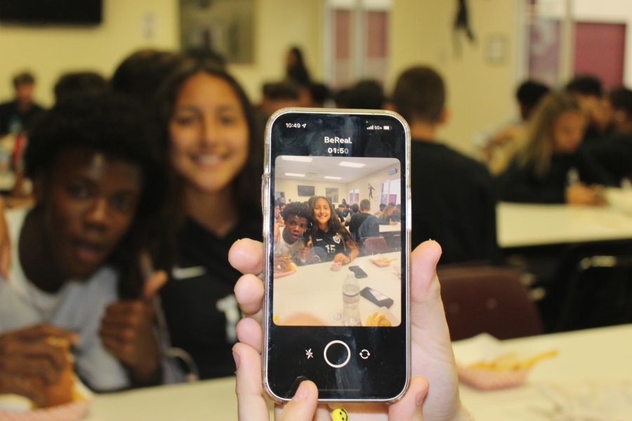 A student holds their phone, capturing their friends and surroundings on the BeReal app.
