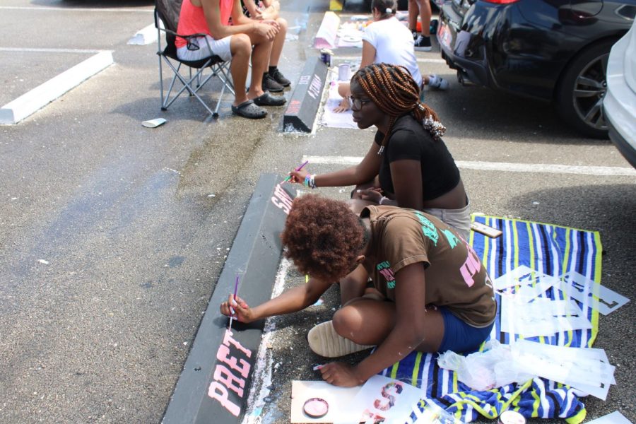 Students use towels to keep dry while painting their parking spots. Unlike the glistening puddles beside them, the seniors’ spots shined a different, unrivaled enthusiasm; after many reschedules, Class of 2023 turned to painting their parking spaces to start the year off with purpose. 
