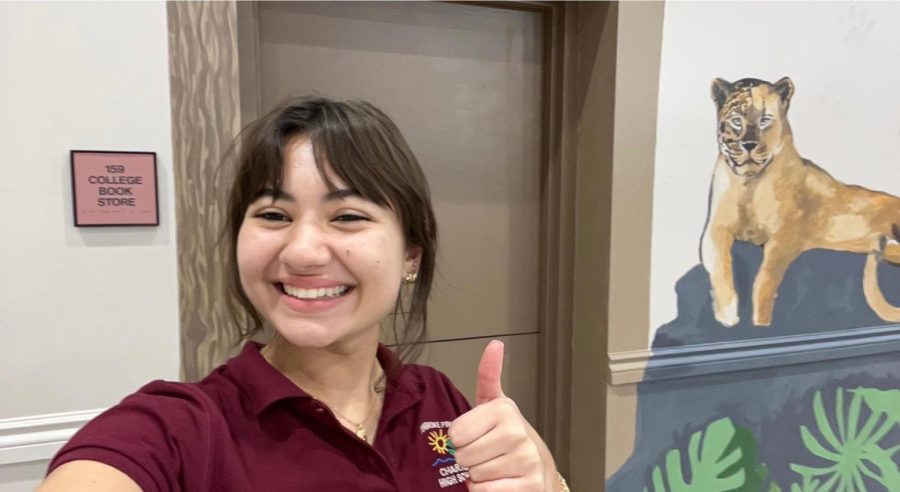 Student Sophia Assis poses behind her mural with a smile and a thumbs-up. And it’s this artistic thumb that made the Jag Shack (the room to the left of Senior Square) what it is today. Stop by the cafeteria to see her work! (Photo donated by: Sophia Assis)