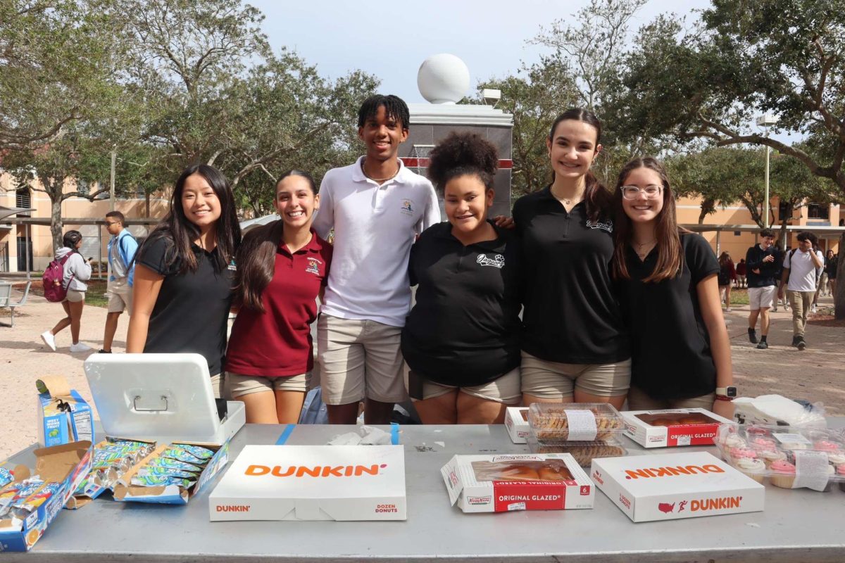 The student council for the Class of 2026 poses for a photo behind a table of their arranged goods. Last Thursday, they sold a variety of snacks to students such as donuts, cookies, cupcakes, and CapriSuns to help raise money for their class!