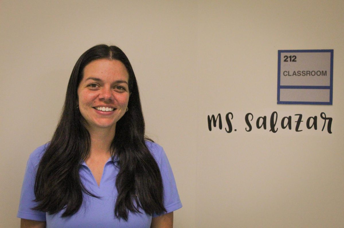 Ms.+Salazar+smiles+as+she+stands+in+front+of+her+classroom.+The+now+mathematics+teacher+attended+Pines+Charter+as+a+student.