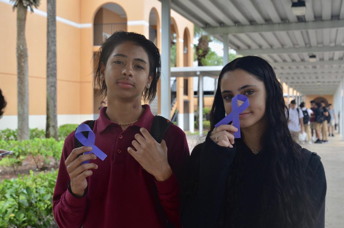 Justin Khan and Analaura Dominguez pose with the symbolic ribbons outside the D Building, showing off the icon for domestic violence awareness. 