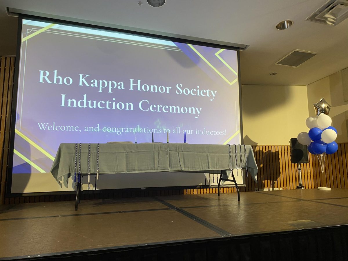 Rho Kappa decorated the auditorium with their signature colors: white, blue, and gold. In the middle is a table with candles that select officers lit to mark the pillars of Rho Kappa.