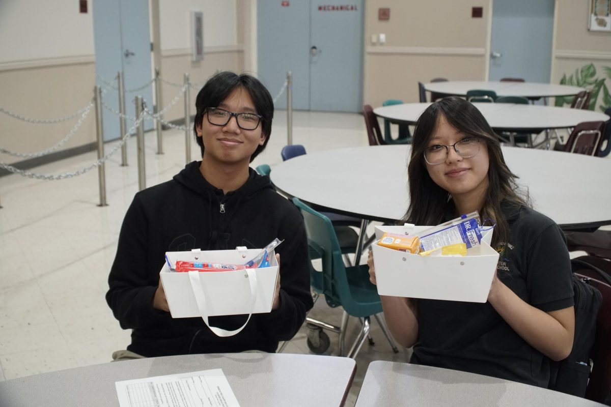 Students in the Hearts for Humanity club pack supplies for people in need on Friday, January 17th in the PPCHS cafeteria. Pictured, two students hold finished boxes to be donated. 
