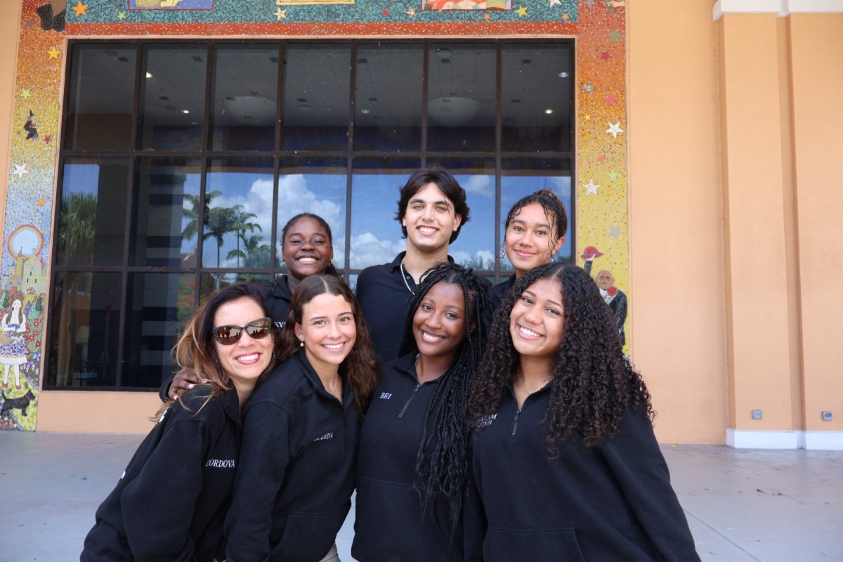 On the River of Grass stairs, Captains of Dance team take a picture of the new 2025-26 board. Starting from the top left row are  senior Captains Kyra Theodore, Anthony Juhe, Amariah Ayum. Starting from the right bottom row are Captains Sjahnaz Buth, Briana Cenatus, Miranda Vidal, and their sponsor Ms. Gil.