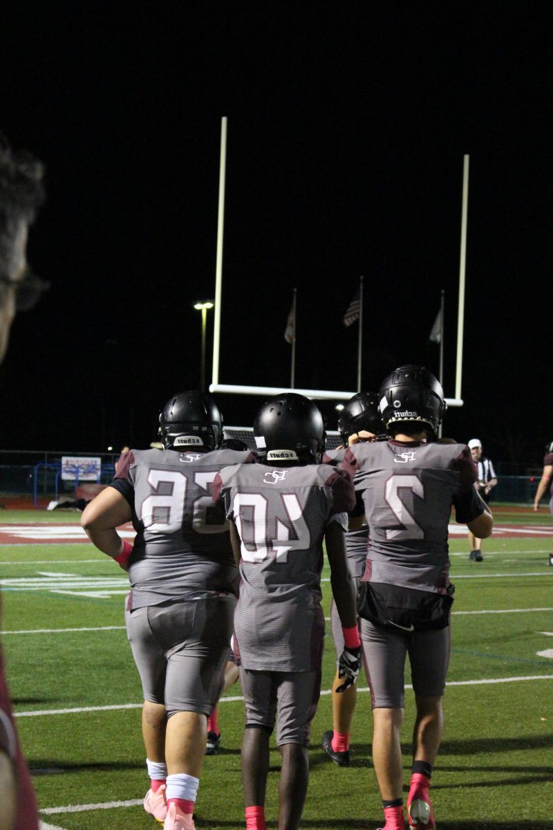 The JV Jags Football team's offense is preparing to rush to the line for the next play after a timeout called by their coach.