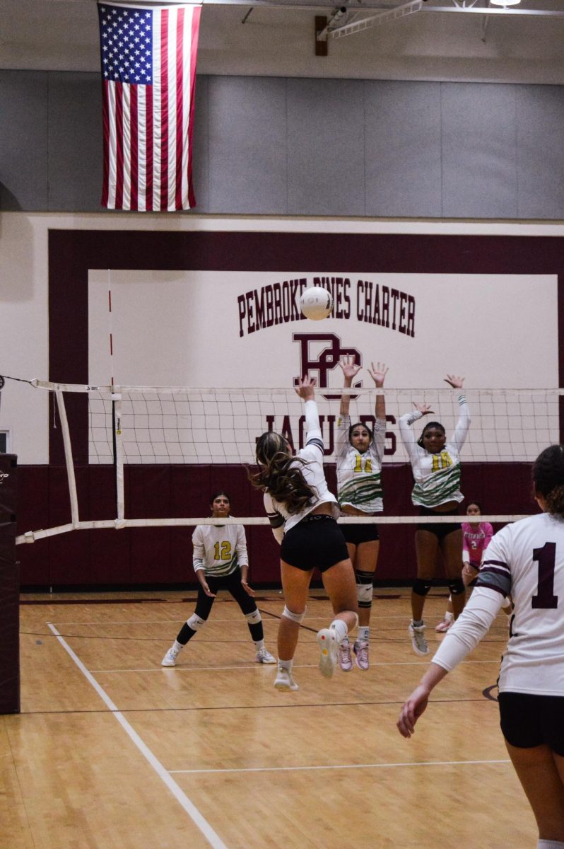 Senior Eva Sofia Hanson is spiking the ball to get the point for her team to take the lead on the scoreboard.
