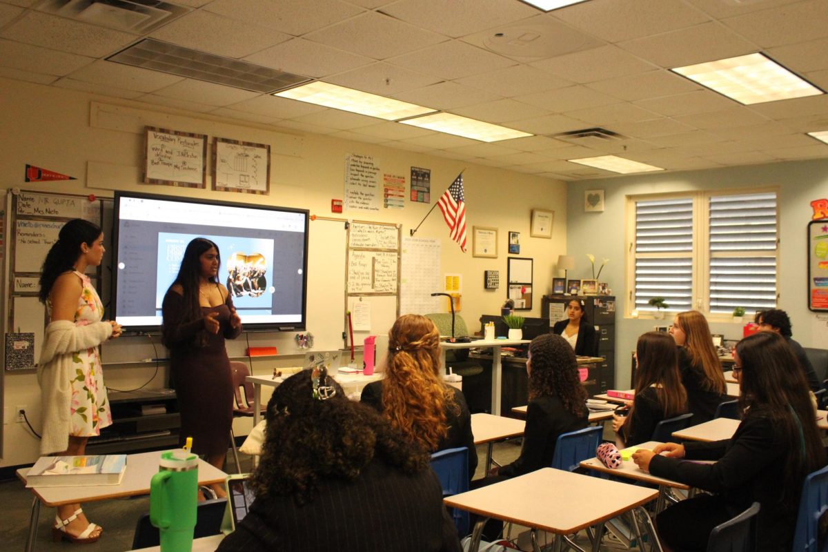 Two board members of Model UN are giving a presentation of specific skills that the students participating need to learn for the event. On the left is junior and Secretary Nusaybah Arif and on the right sitting down is sophomore and Historian Daniel D' Souza.
