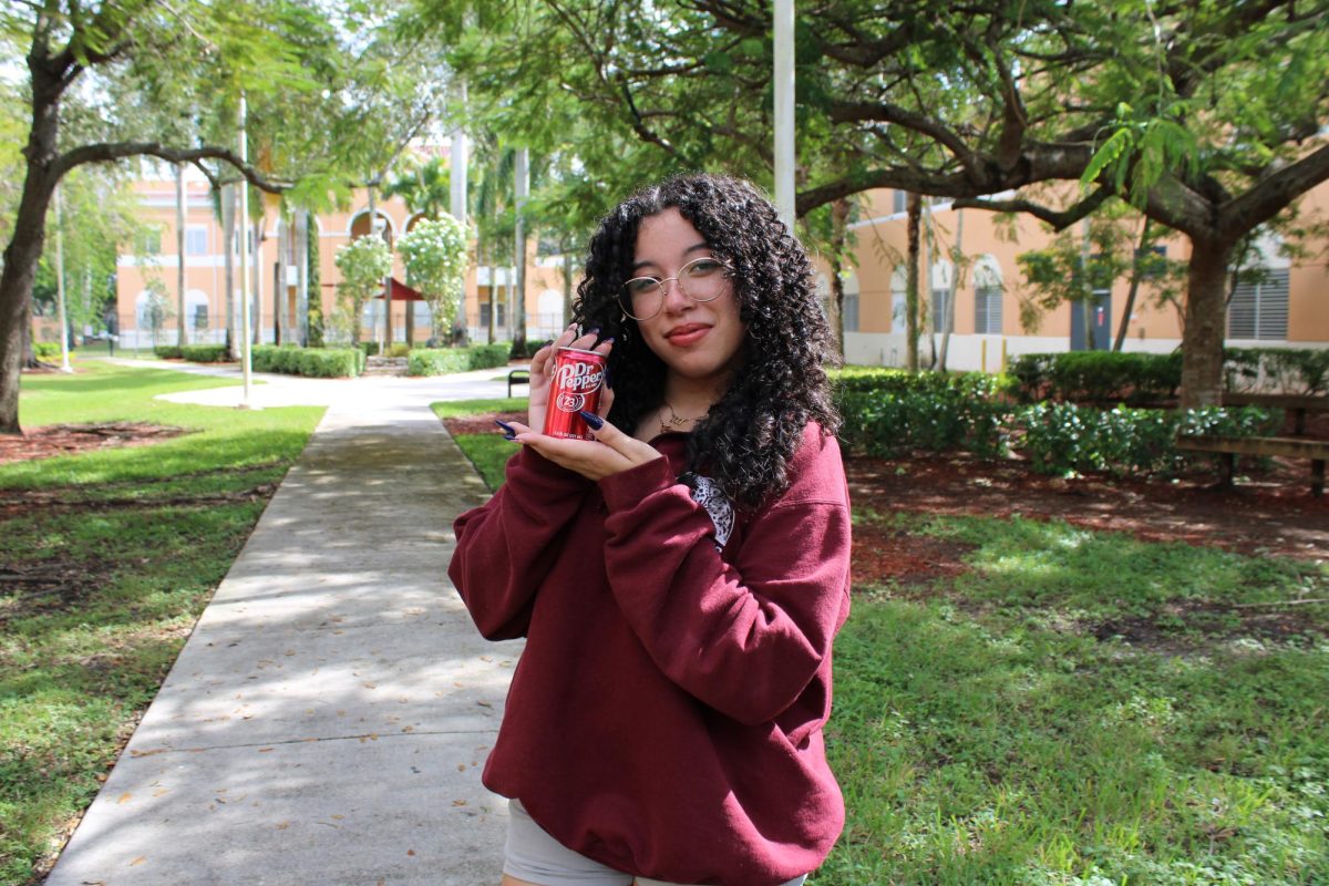 Gabriella Perez smiling at the camera while holding a can of Dr. Pepper.