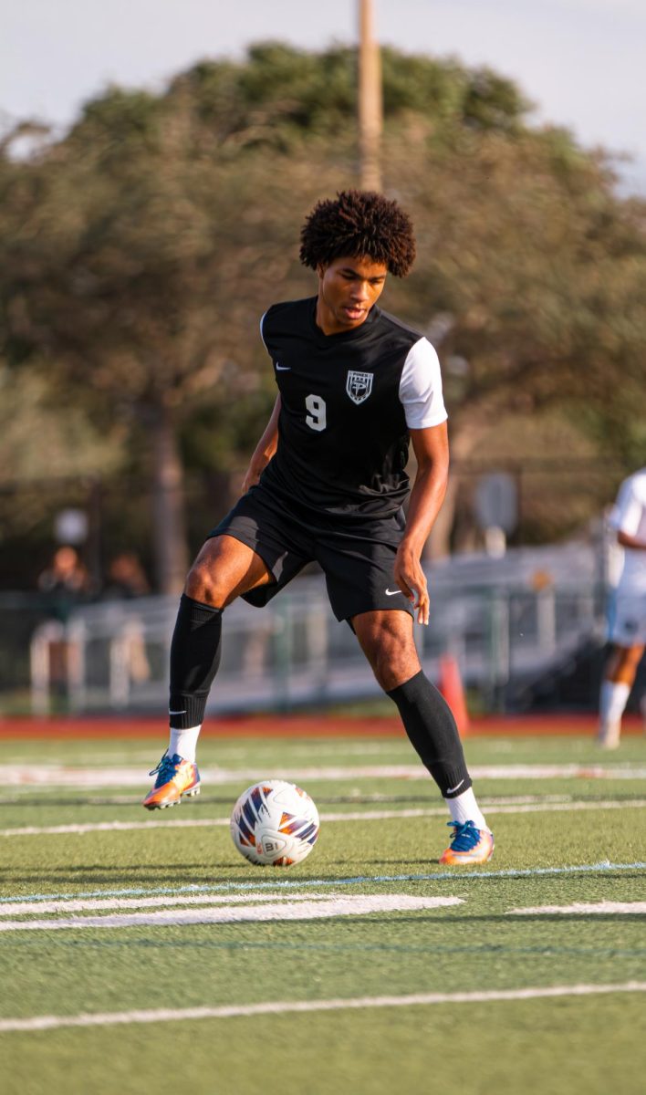 Senior Ty Chantrelle, a varsity jaguar on the soccer team as he dribbles the soccer ball aiming to make a goal.