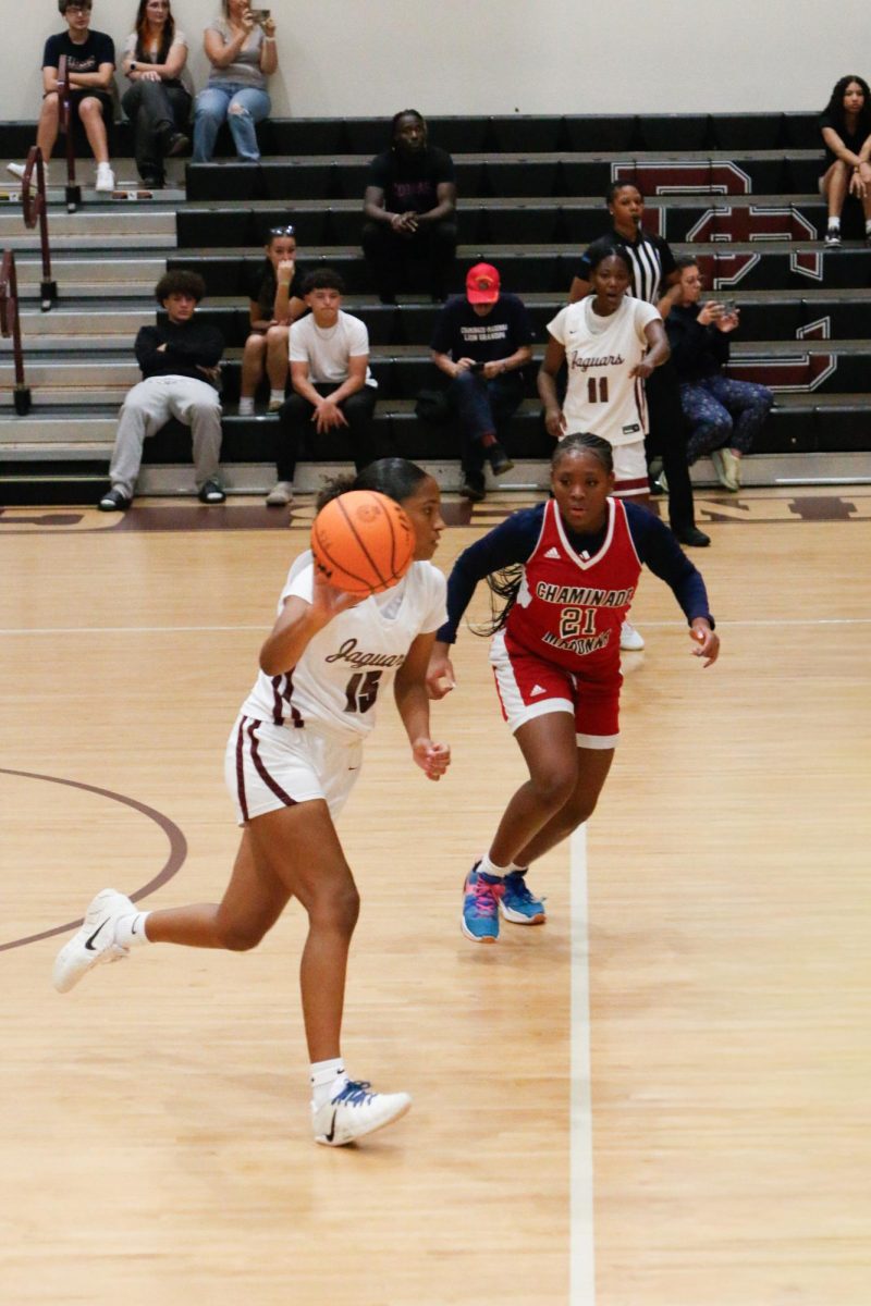 Sophomore Soule Osborne [#15] as she runs with the ball while dribbling it attempting to make a layup.