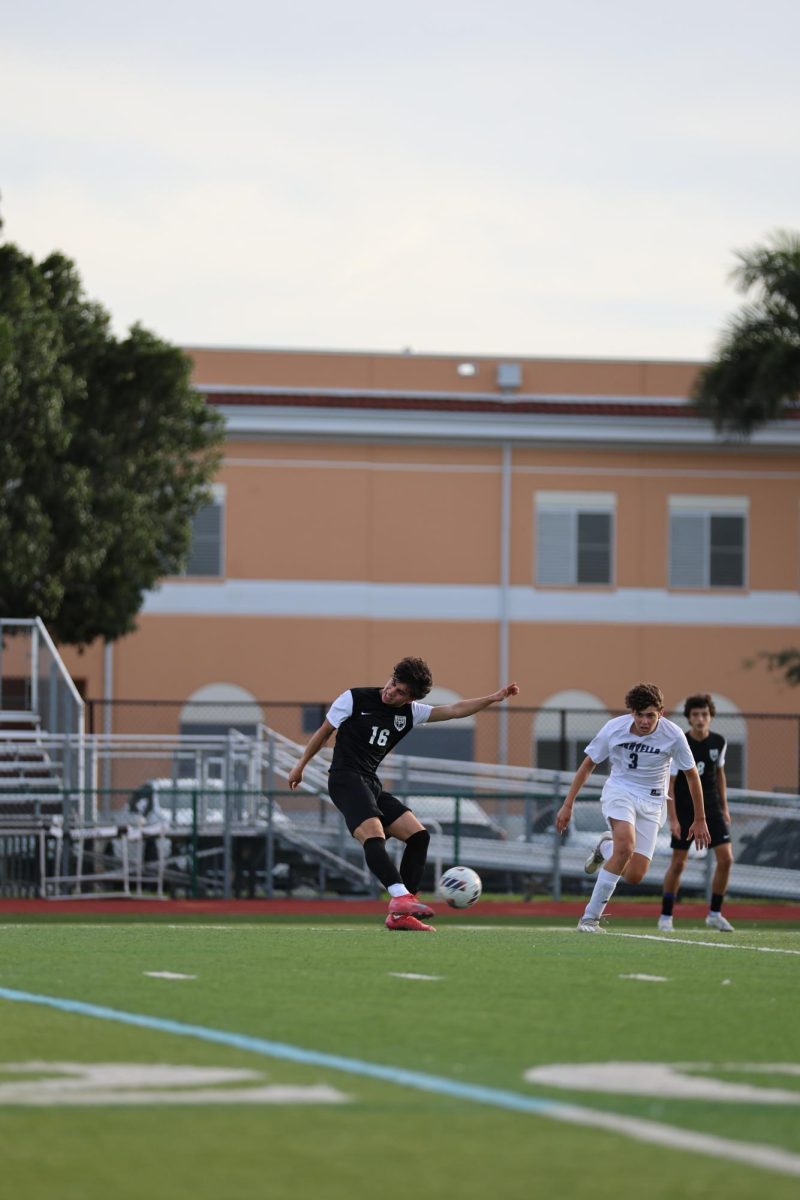 Senior Daniel Fletcher [#16] on the Jaguars boys soccer team as he kicks the ball with all of the strength from his body in an attempt to score a goal.