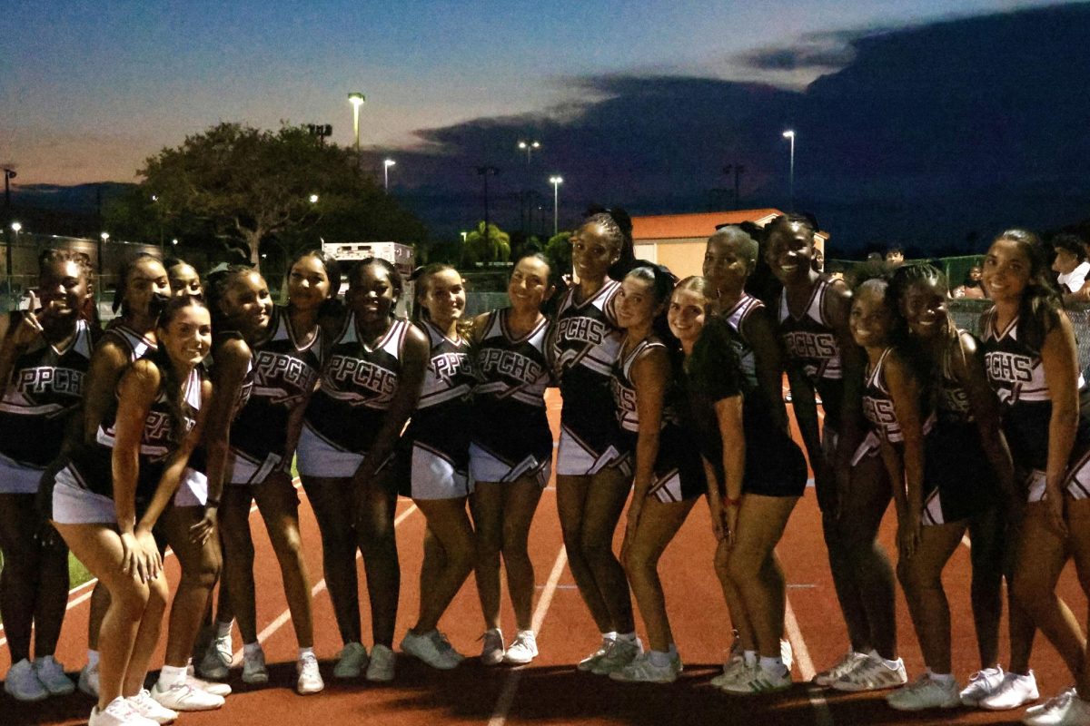 The Lady Jags varsity cheer team stand alongside the sidelines of the varsity football games together posing for a photo.