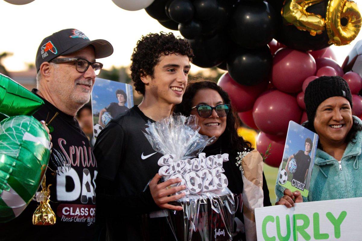 Senior Julian Iodice as he stands alongside his family in front of the Class of 26' backdrop before the Jaguars soccer team's senior night game. During the game, he scored a goal.