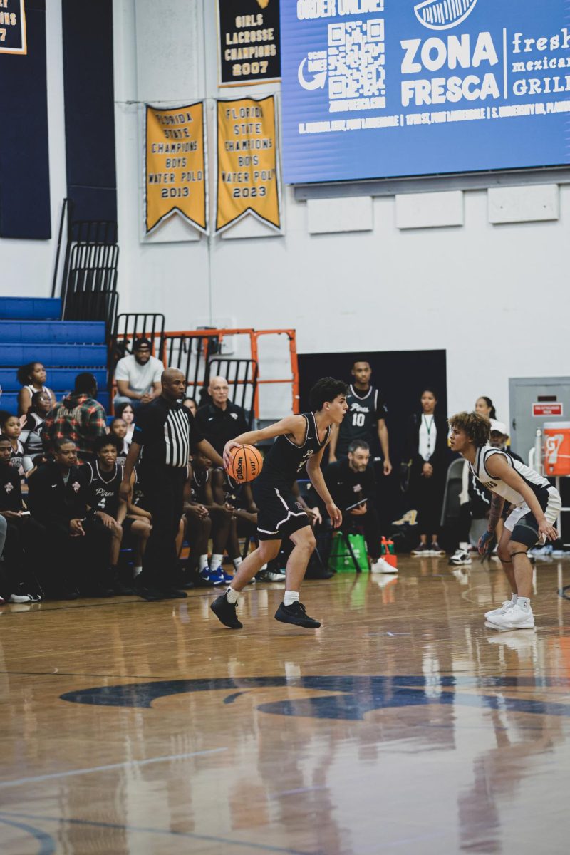Junior Alex Vardakis dribbles the basketball at an away game. After this photo was taken, he made a three-pointer.