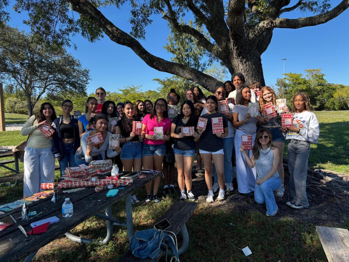 Members of both the National English Honor Society and the Youth Literacy Project pose at C. B. Smith Park with their wrapped books. The books will go to families at the elementary charter system.