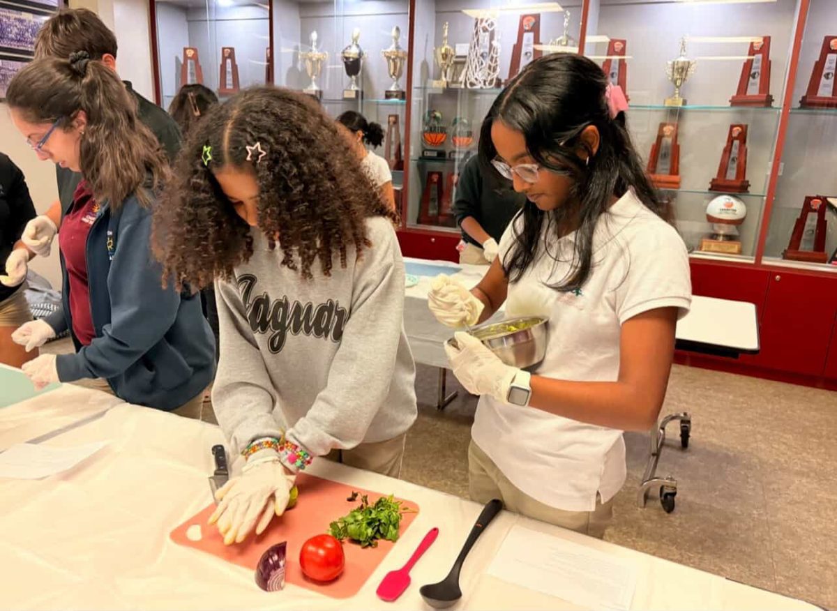 One Culinary Club member cuts ingredients to make guacamole, while another mixes the dip together.