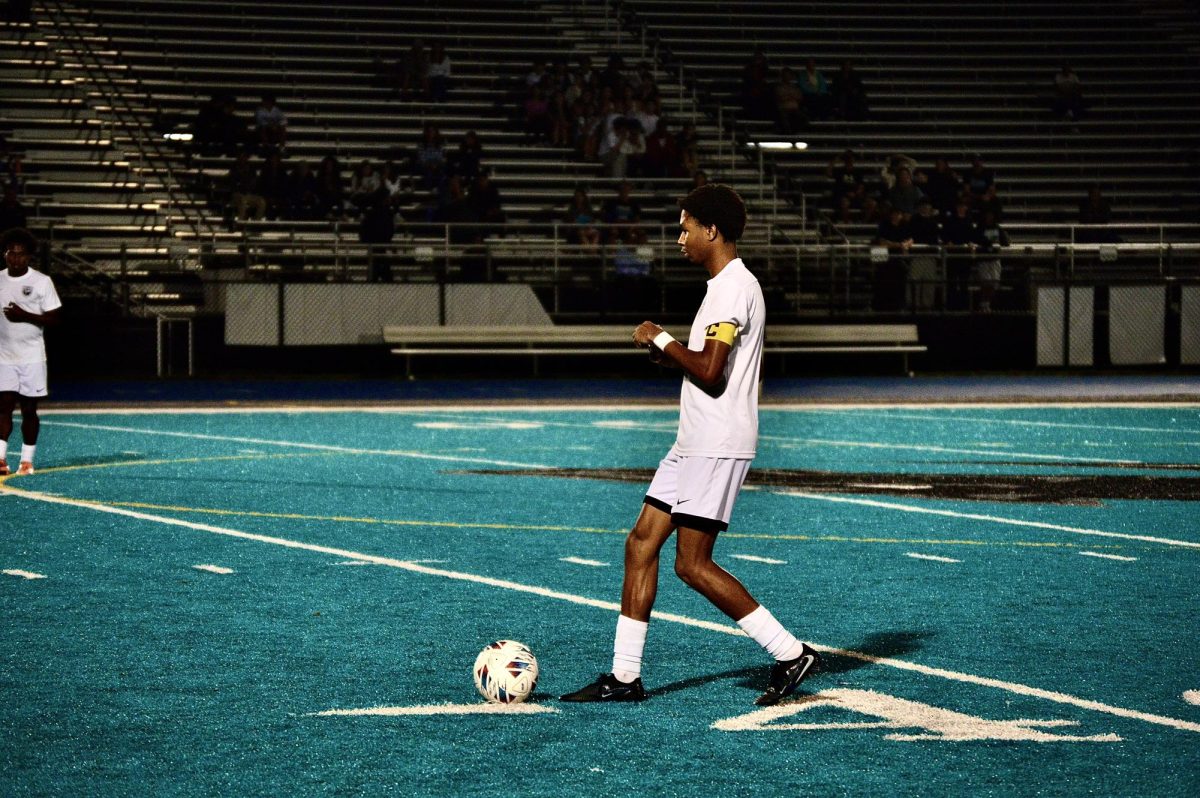 Senior Noah Lewis kicks the ball on the soccer field, aiming to dominate in the playoffs.
