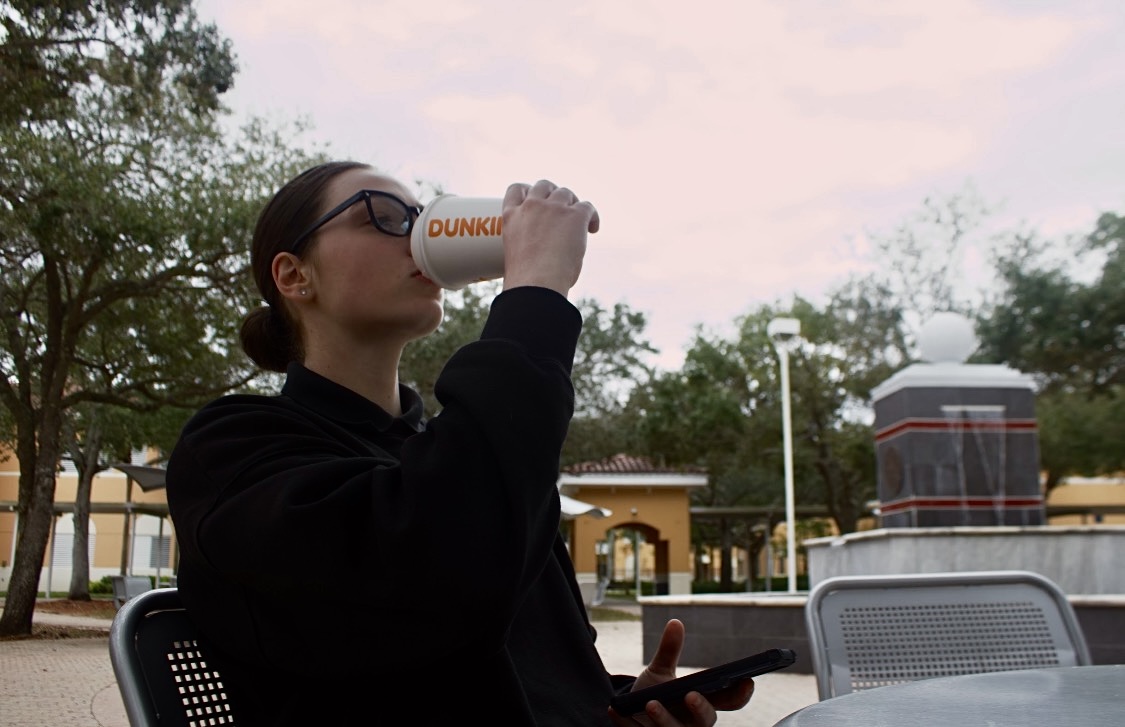 Pembroke Pines Charter student drinks a Dunkin coffee to get through her day, then glances at her phone only to continue the cycle.