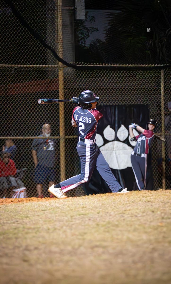 Sophomore Cyrus De Jesus swinging his bat to make contact with the baseball.