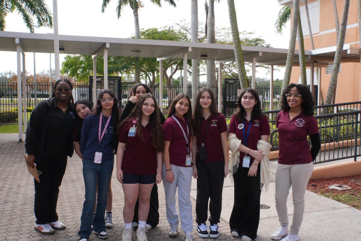 Seniors Eri Fatimilehin (left) and Madison Hall (right) smile with their group of middle schoolers. They led the students around campus for their eighth-grade orientation.
