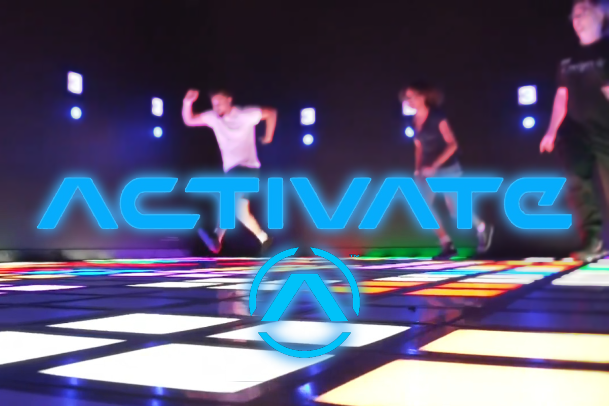 Three people in the background playing one of the many minigames offered at Activate. This one in particular consists of jumping onto the colored tiles.