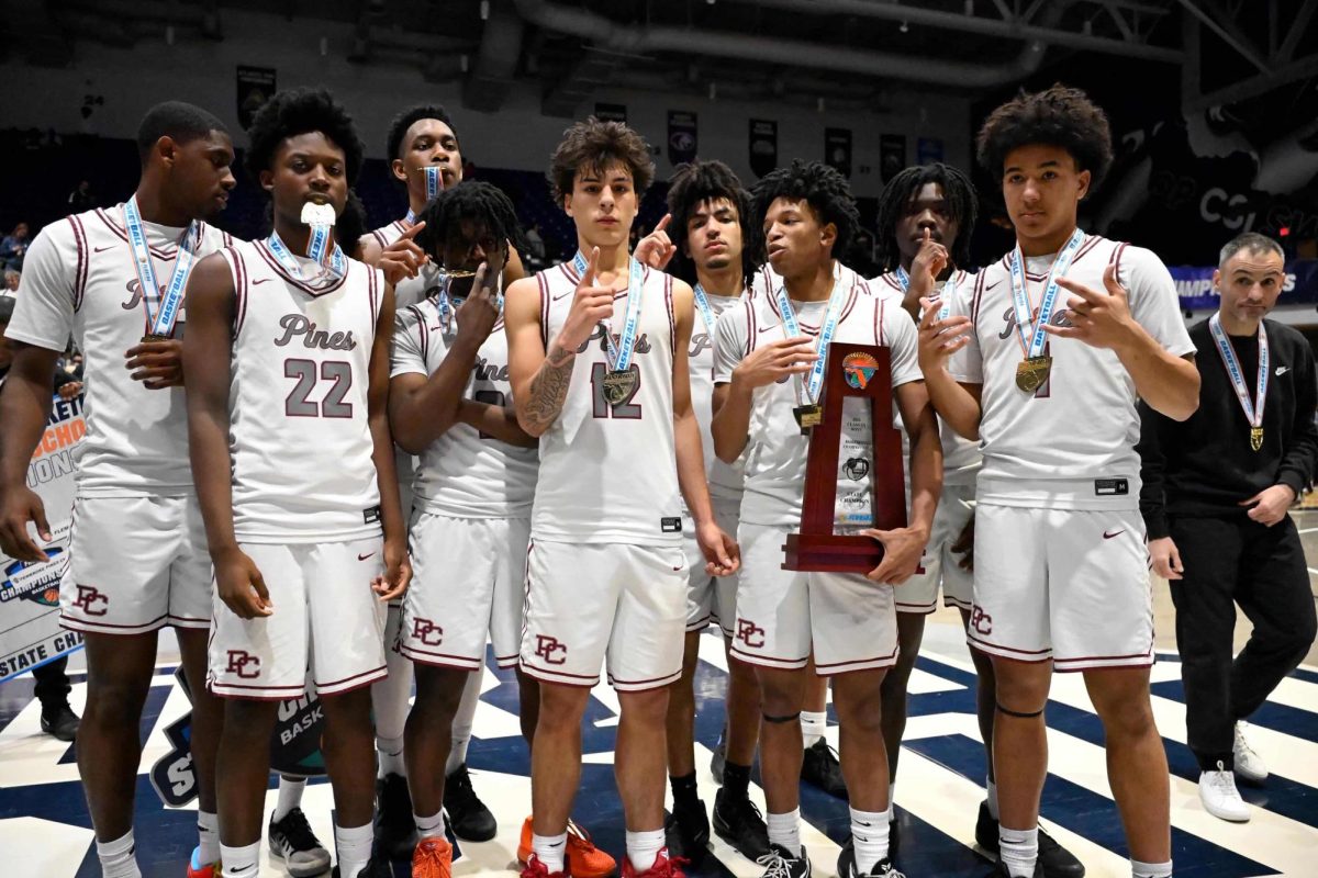The Jaguars basketball team standing together to pose for a photo with their state champion trophy and medals.