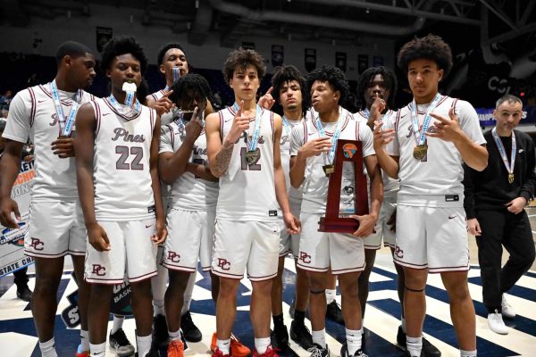 The Jaguars basketball team standing together to pose for a photo with their state champion trophy and medals.