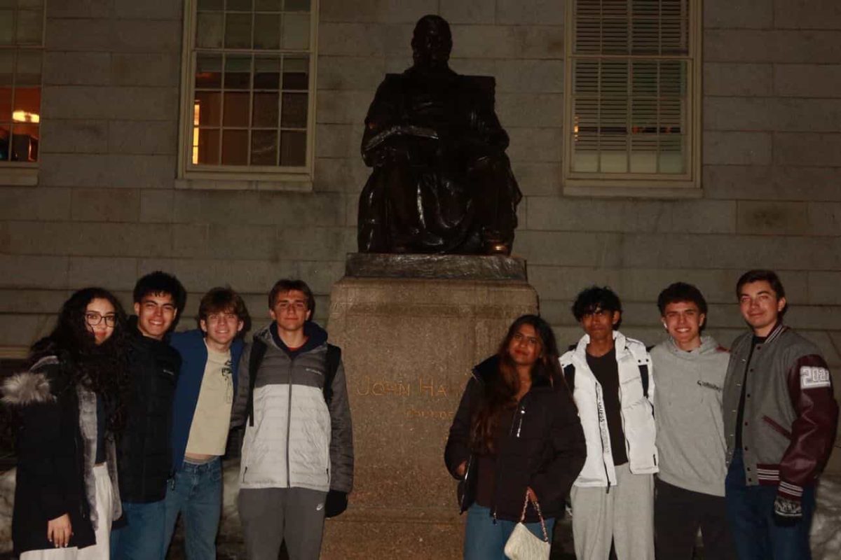 The debate teach stand together around a statue on their trip to Massachusetts for their competition at Harvard.
