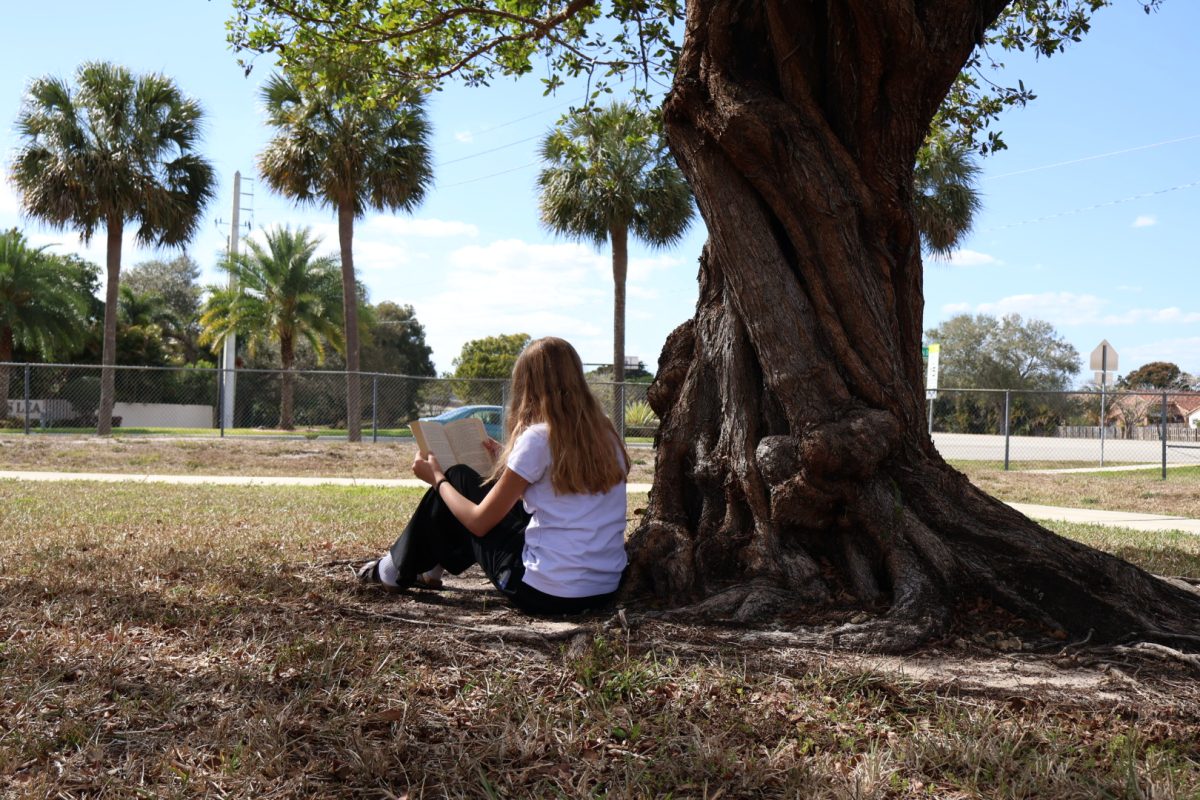 PPCHS Freshman River Furgeson sits next to a tree and reads a book as she enjoys the peace and quiet of her day. It resembles how you can gain a moment of quietness no matter where you are and enjoy the moments of not worrying about academics or extracurriculars.