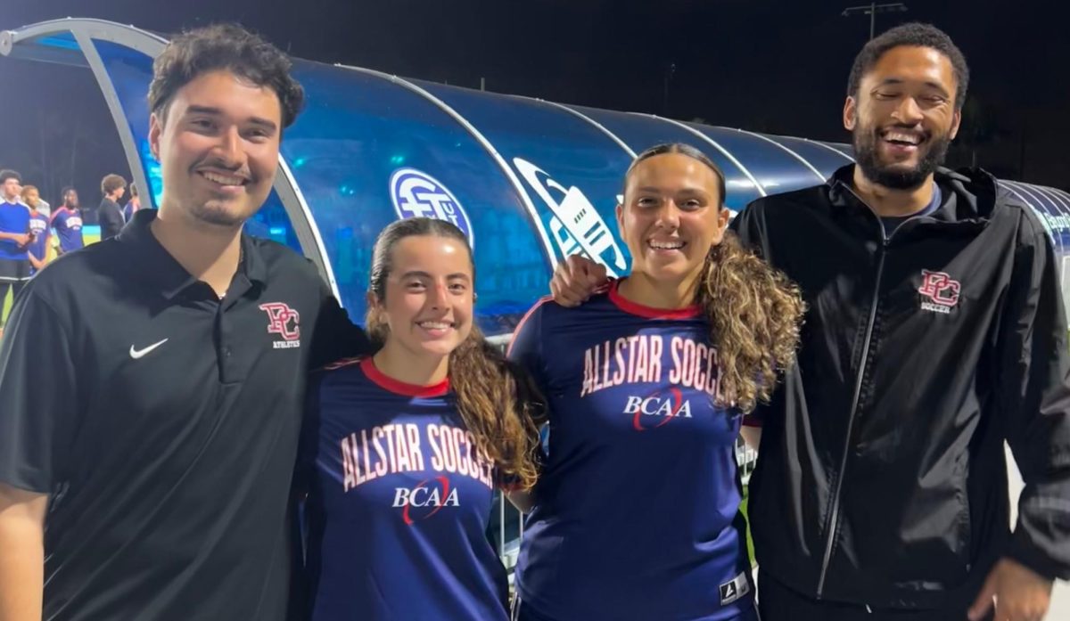 Seniors Madison Cassanova and Catalina Castro standing alongside their coaches, Lemmers Lyndon and Lemmers Lukas for their final high school soccer photo.