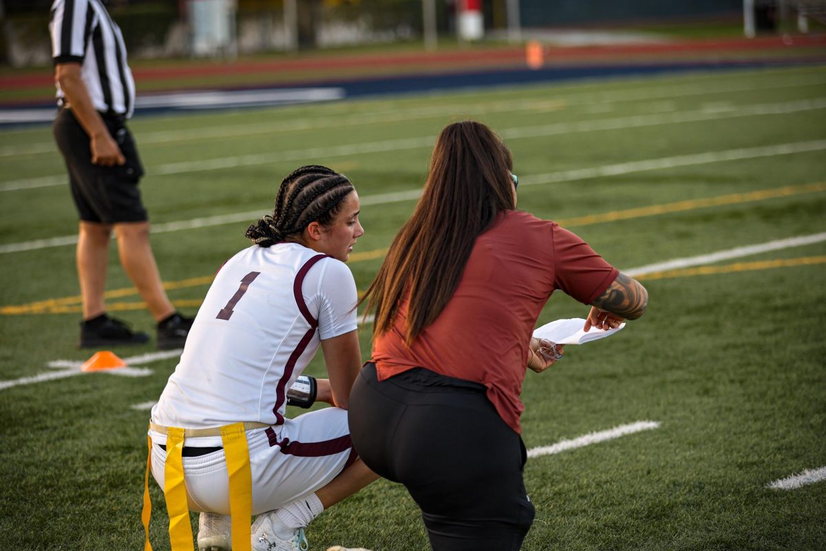 Lady Jags flag football quarterback, Makenzie Ojeda planning the next play of the game with her coach.