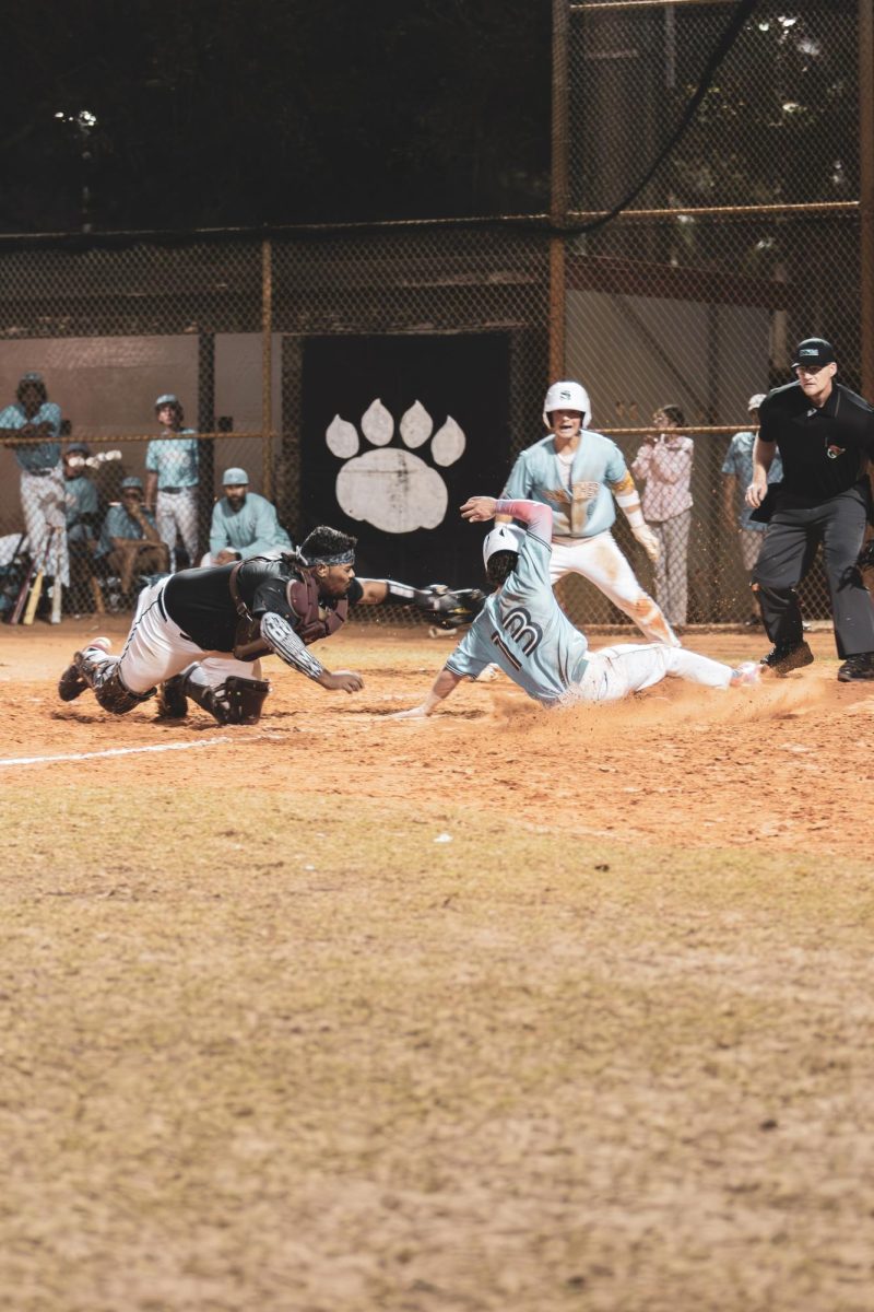 Junior catcher Jack Anthony Hernandez diving to make the tag at home.