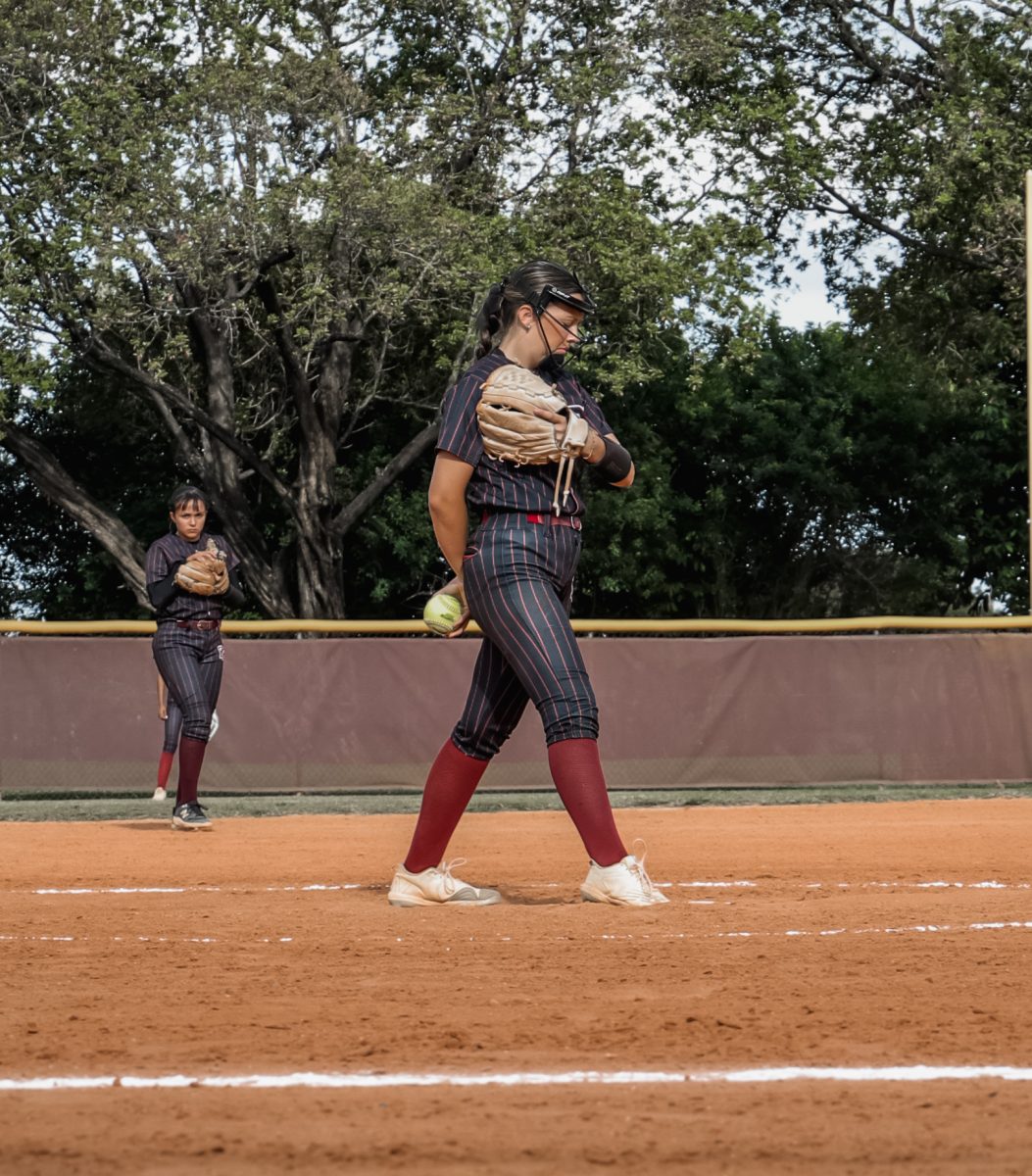 Junior Destiney Ortega reads her signs as her coach and the catcher signal to her what pitch to throw to the batter.