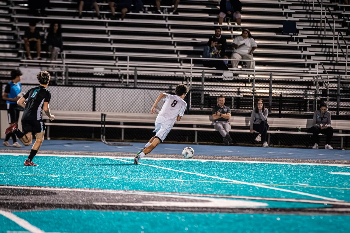 Senior Julian Iodice (#8) running with the soccer ball to attempt to score a goal.