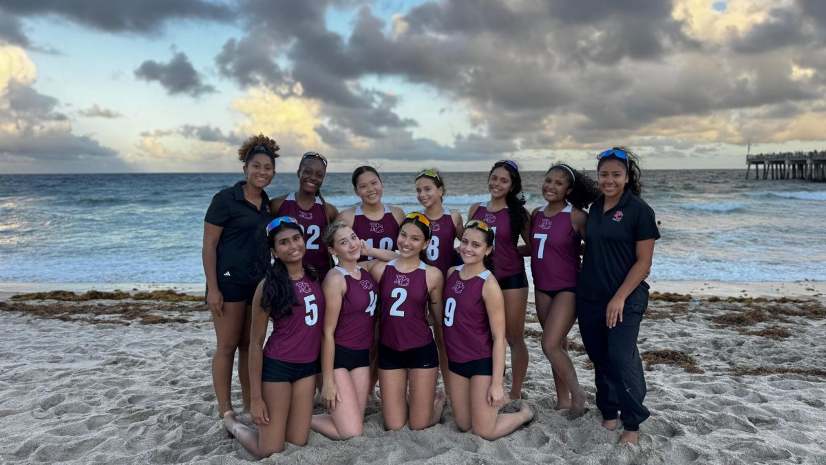 The Lady Jags beach volleyball team poses for a picture together on Hollywood beach in the sand.