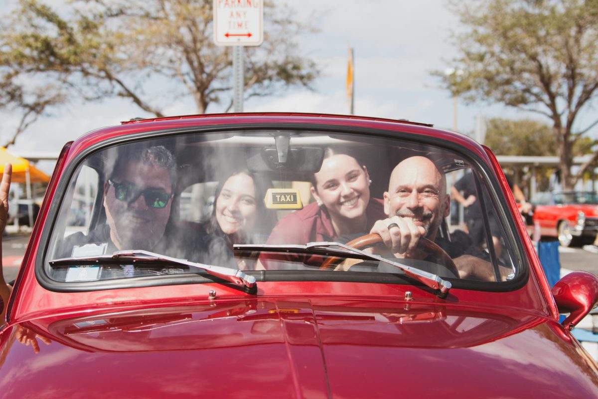(Read left to right) Dan Capiro, Lila Peterseil, Sophia Peterseil, and Principal Peter Bayer, our principle, all come together for a photo in a red, vintage car while showing their appreciation and excitement for this school's first ever car show.