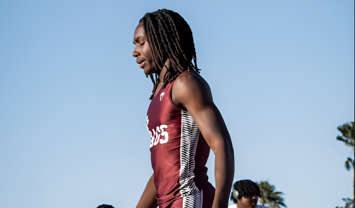 Junior Jahsai Juste at a track meet in his uniform walking along the track. 