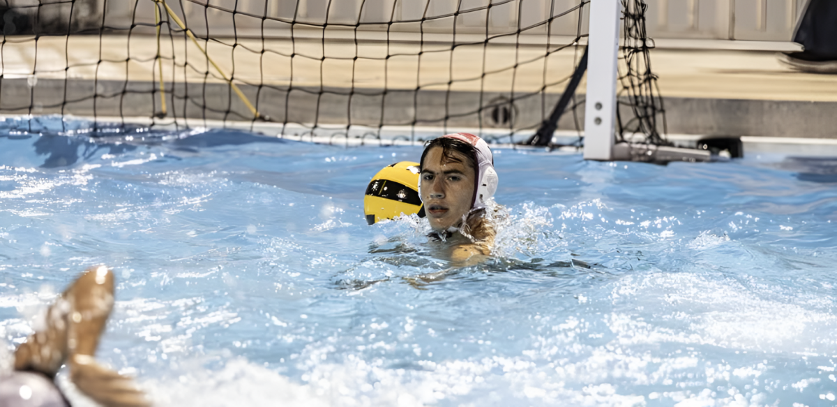 Senior captain David Hernandez holding the water polo ball during a game planning his next move.