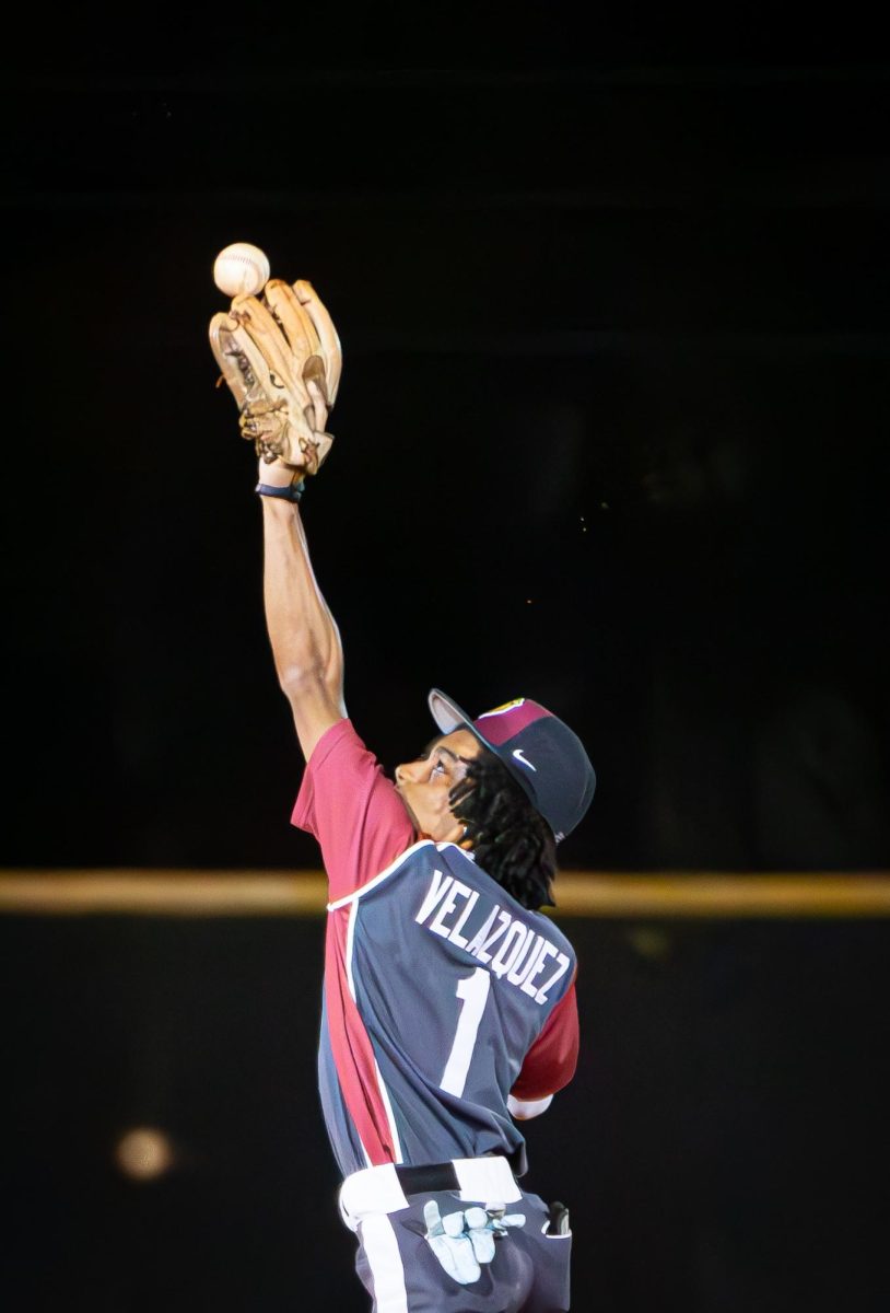 Senior Aydan Velazquez (#1) as he throws his arm up to catch a line drive at second base during a game.
