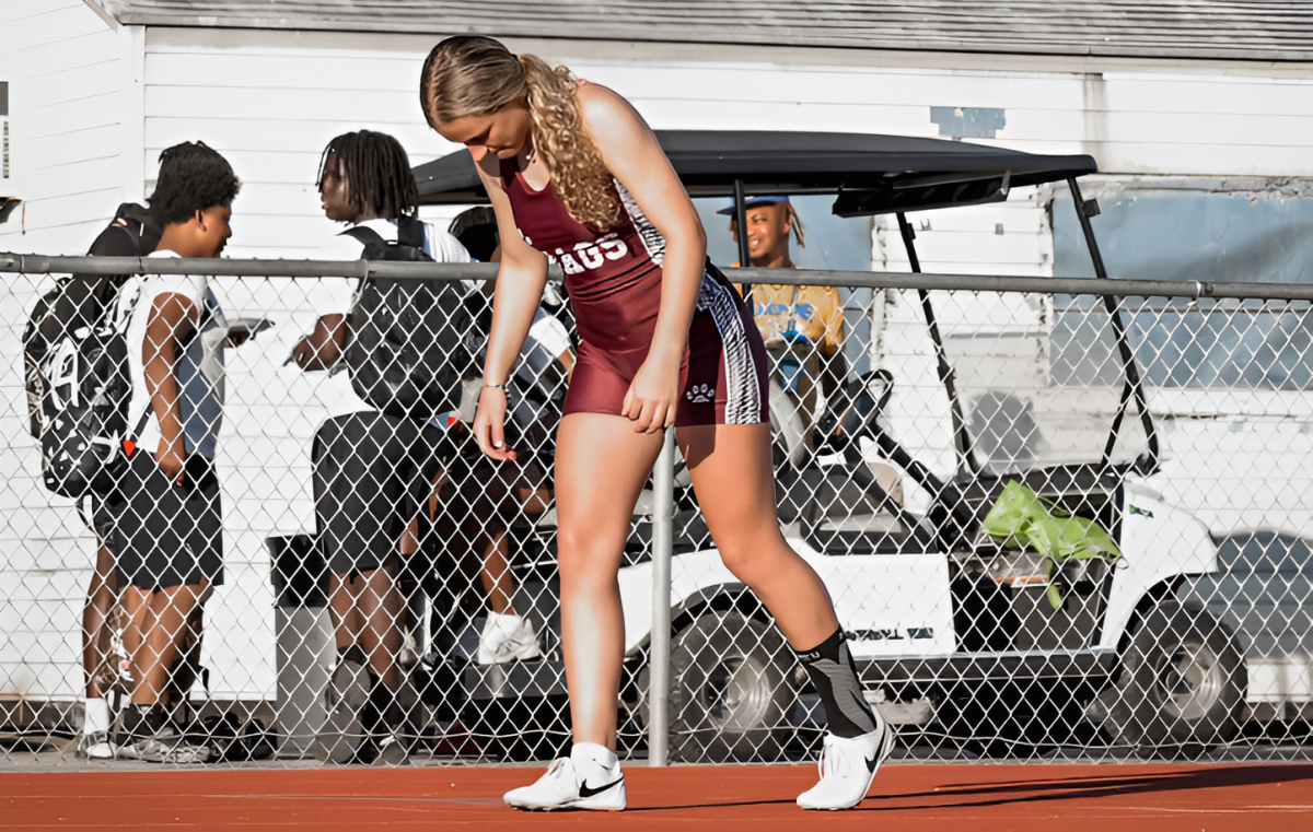 Senior Lauren Pfeiffer setting her feet on the track preparing to take off and run.