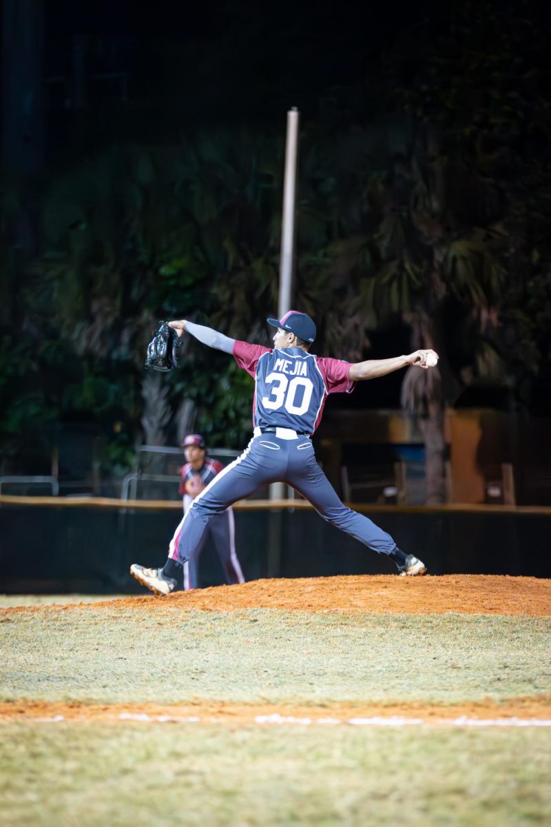 Sophomore Fabrixio Mejia (#30) extending his arm to throw the baseball while pitching.