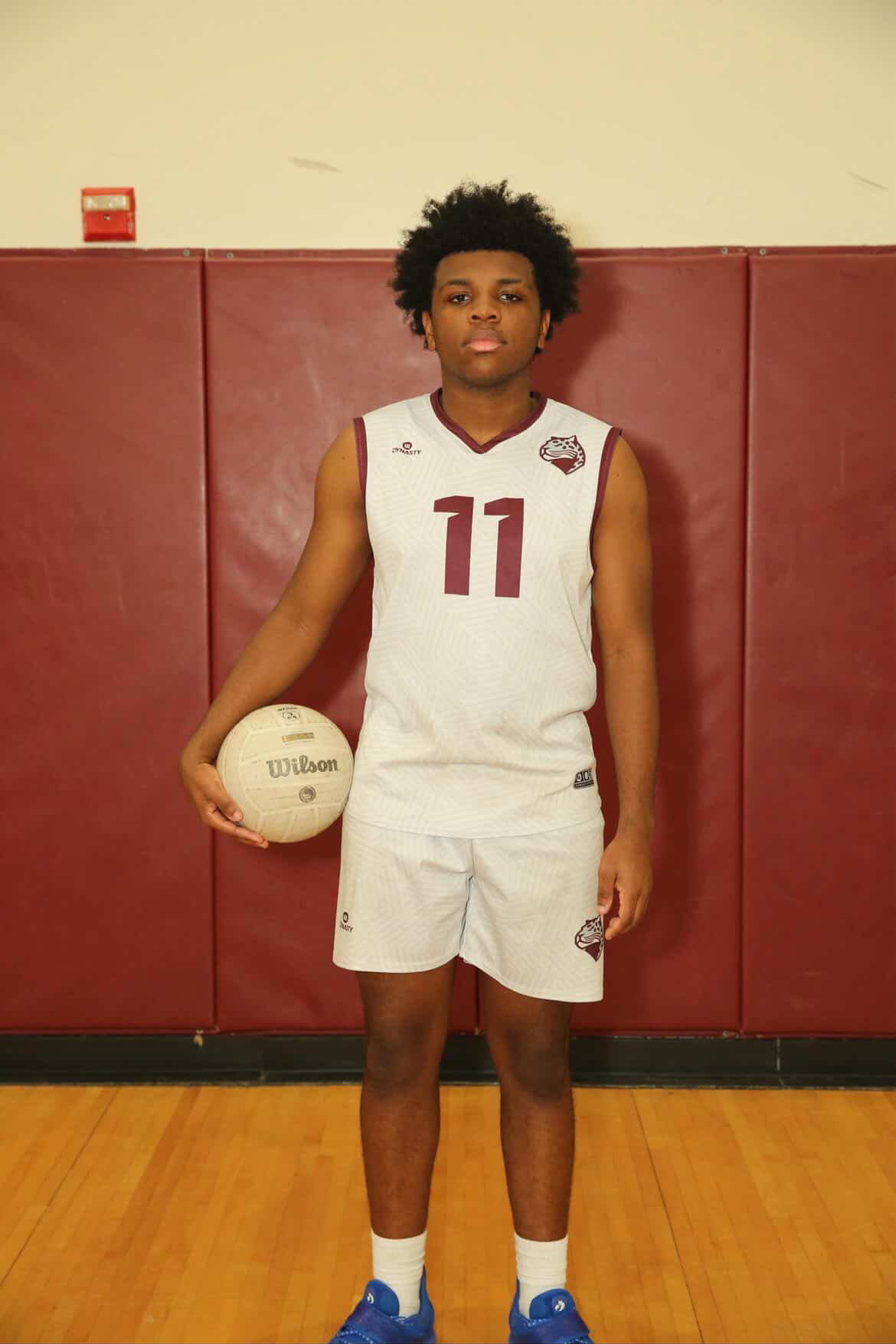 Senior Daren Raphael (#11) posing for his senior photo while holding a volleyball.