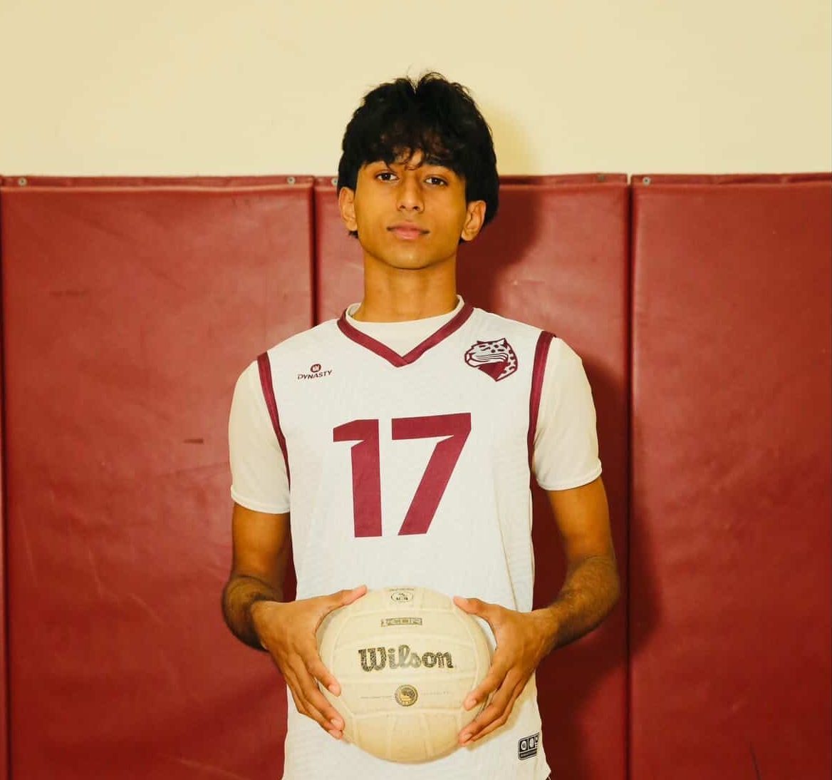 Senior Godly Thomas (#17) posing for his senior photo with his jersey on and volleyball in his hands.