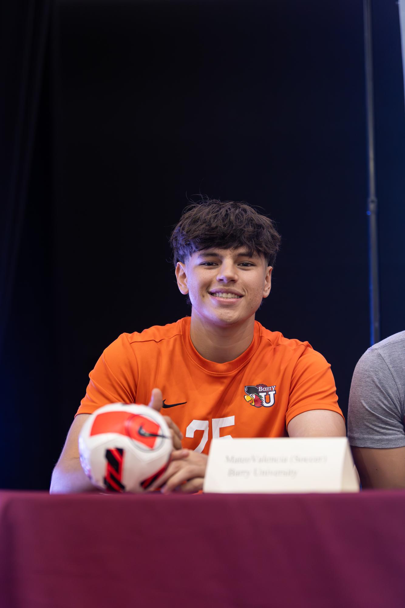 Senior Mateo Valencia smiles at the camera on signing day with his future jersey on. 