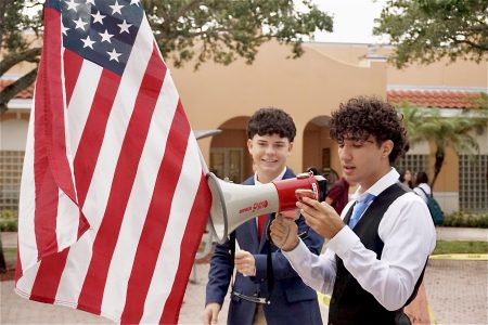 A PPCHS senior smiles while holding an American flag. His friend reads a section from the Constitution through a loud megaphone. Photo by: <a href="https://ppchsnews.com/staff_profile/gianna-medina/">Gianna Medina</a>