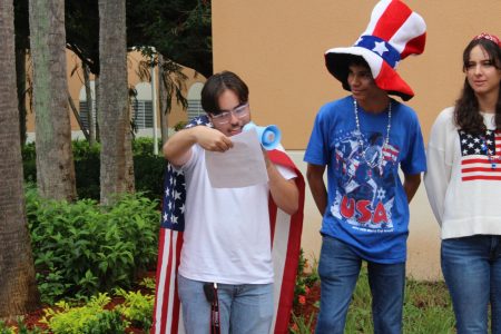 CHAT Newspaper Digital Editor in Chief Evan Omana recites the Constitution with a flag across his back. His group stands beside him, cheering him on.
Photo by: River Ferguson <a href="https://ppchsnews.com/staff_profile/river-ferguson/">River Ferguson</a>