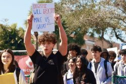 Junior Alejandro Escudero holds his sign, which reads "Hate will not make us great".